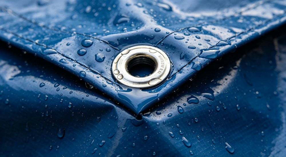 Close up detail of heavy duty waterproof tarpaulin material showing waterproof coating reinforced corners metal grommets