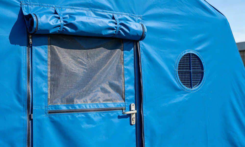 Close-up detail of emergency frame tent entrance door, window with mosquito netting, and ventilation vent