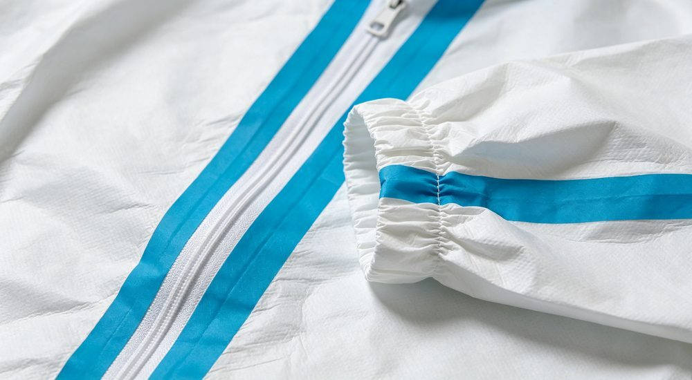 Close-up detail of medical coverall blue seam tape with zipper and elastic cuff on white fabric
