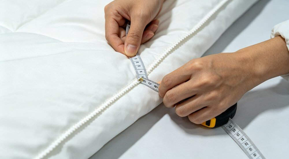 Closeup QC inspection of stitching density on institutional bedding fabric