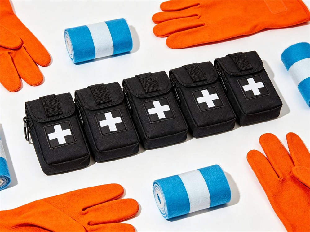 Product shot of five standardized medical kits in different colors black orange blue red green each with white cross arranged in row on white background