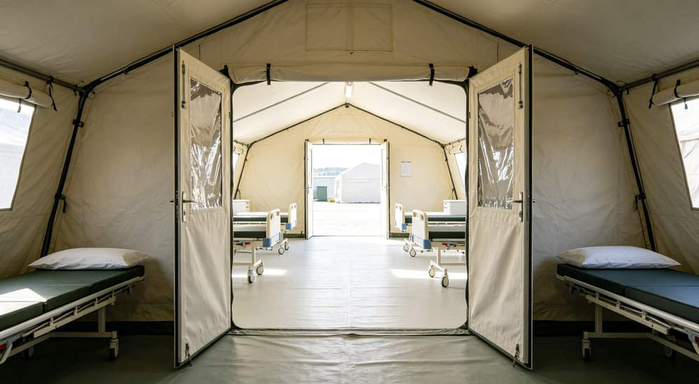 Military field base deployment showing emergency tents used for troop accommodation command posts and operational support in remote field conditions with security perimeter