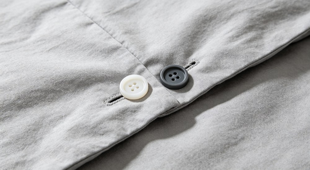 Close-up of quality control staff testing bedding sample with measuring tape, inspecting duvet cover dimensions for institutional procurement approval and specification