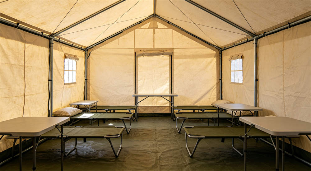 Interior of 12 square meter steel frame relief tent with cots and foldable tables, steel poles visible at corners, humanitarian shelter accommodation for displaced families