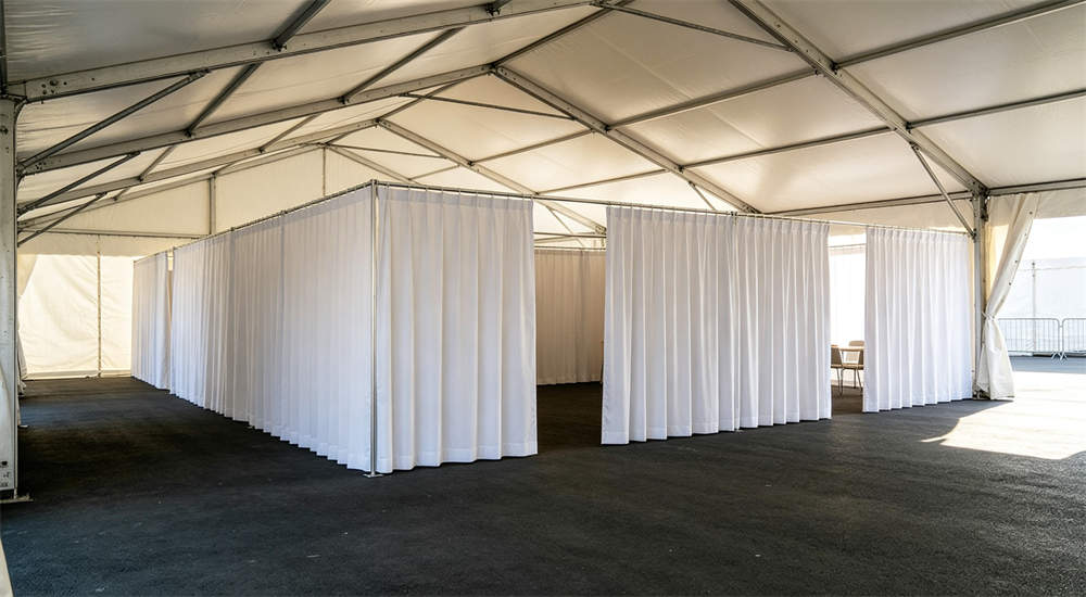 frame tent with white fabric partition curtains creating divided indoor space for temporary institutional use