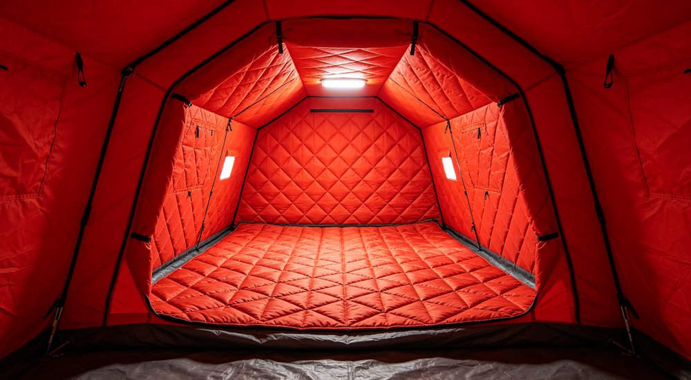 45 degree angle view of 20 square meter red fire rescue inflatable tent with firefighter standing at entrance, medium size command post layout, dual door design, professional product photography on concrete surface