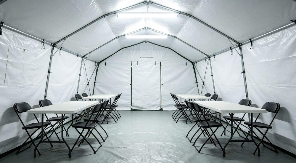 High-quality photo of a 40 square meter inflatable disaster relief tent interior panoramic view showing spacious layout used in disaster relief and humanitarian aid operations in white color with red cross medical markings