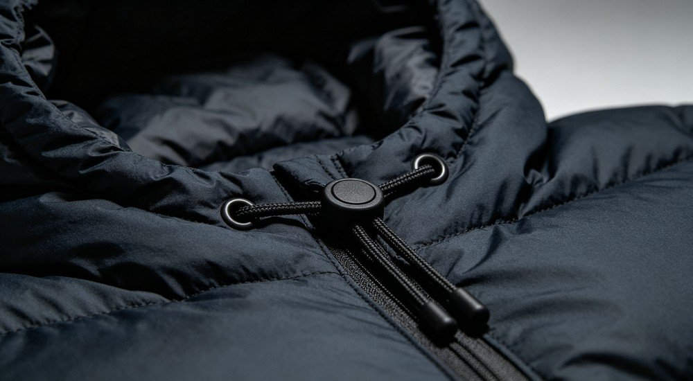 Close‑up shot of sleeping bag hood drawstring toggle adjustment, reinforced stitching and cord lock detail, product accessory macro photography