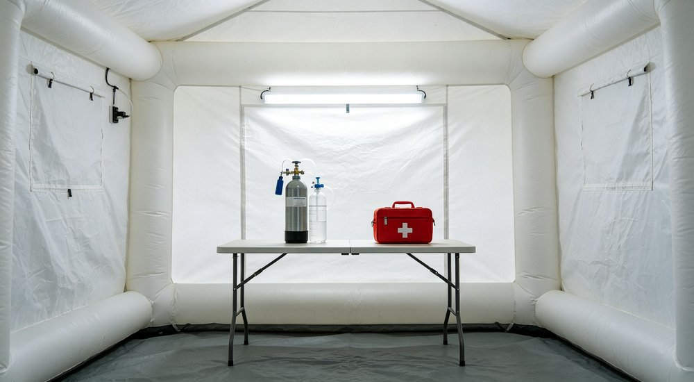 Medical equipment setup inside inflatable tent with portable devices, bright interior red and white inflatable emergency shelter for disaster relief operations