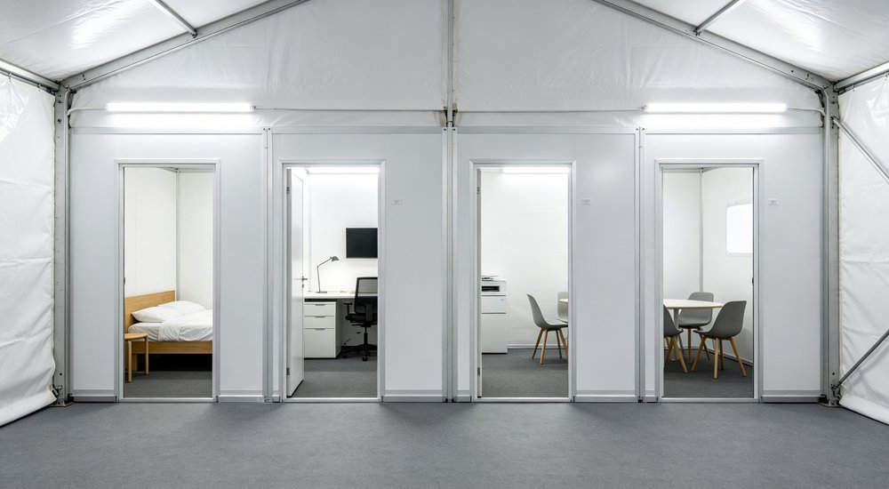 Interior connected corridor of modular inflatable tent system showing passage between modules, bright lighting red and white inflatable emergency shelter for disaster relief operations