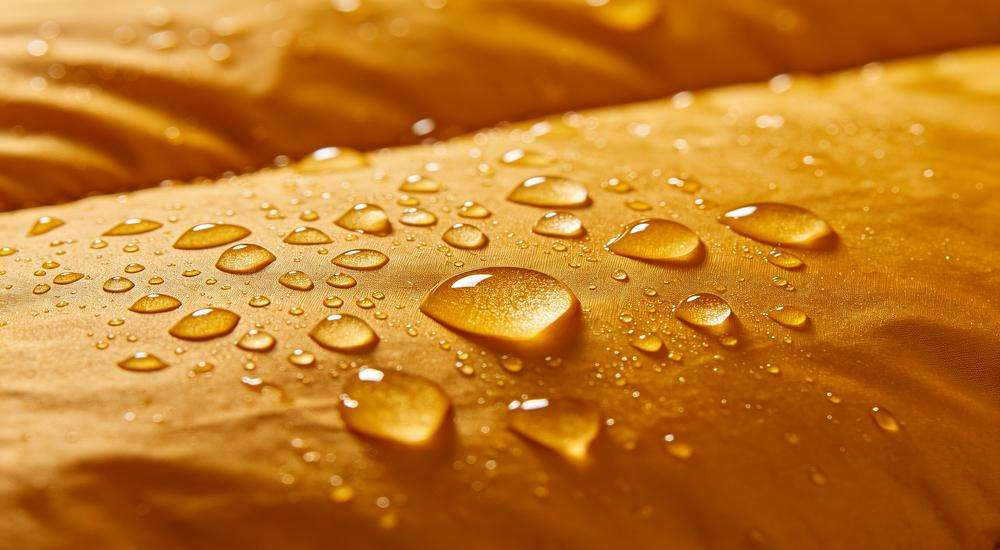 Close up of water droplets rolling off sleeping bag outer fabric, waterproof DWR coating test, macro product photography