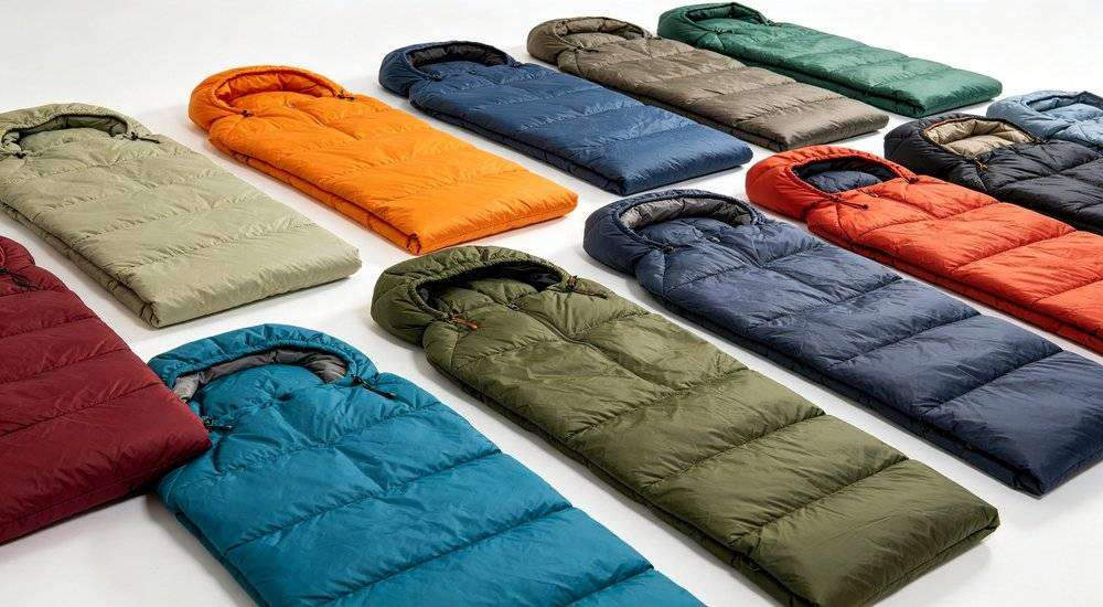 Wide angle view of multiple bulk sleeping bags in different colors arranged neatly on white background studio