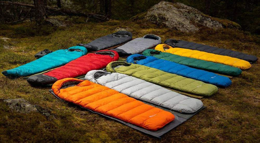 Wide angle view of colorful sleeping bag collection various colors product variety outdoor natural setting