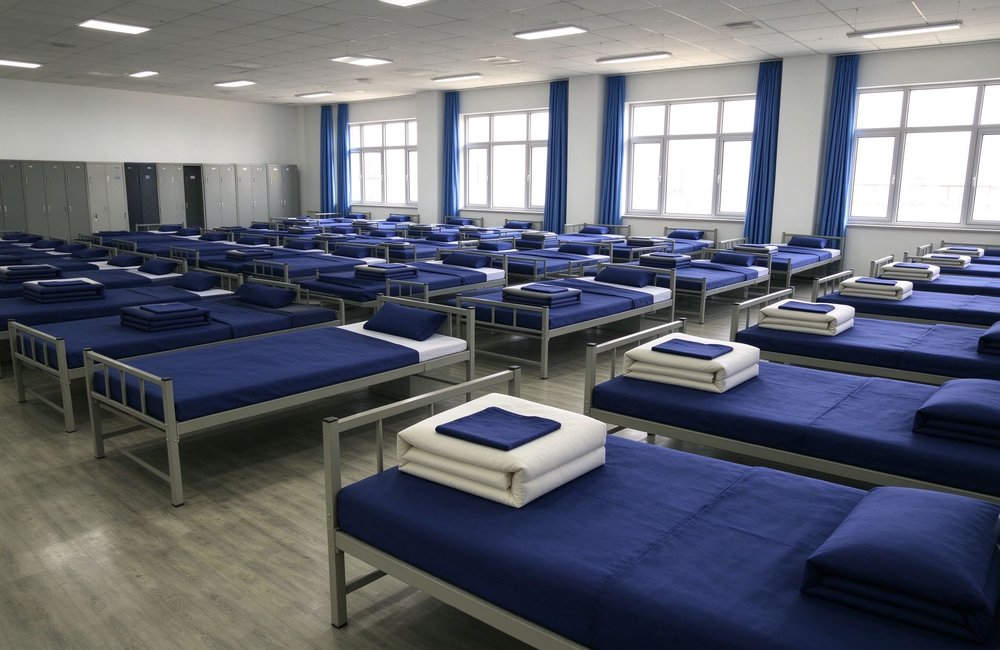 Fire station dormitory panorama with rows of beds with fire station bedding neatly arranged for firefighter living quarters institutional bulk bedding