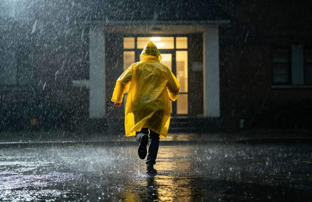 Open bulk thunderstorm emergency kit laid out with waterproof radio, LED headlamp, multi-size rain ponchos and first aid supplies for shelter procurement.