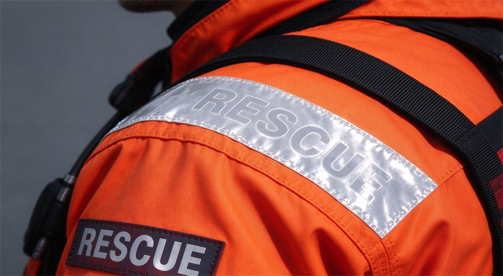 Product detail of SOLAS grade reflective tape on orange ice rescue suit shoulders with bright silver reflective strips and RESCUE identification for whiteout visibility