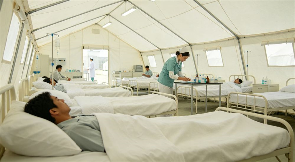 Inside a refugee camp shelter using emergency shelter bedding, durable relief linen on a simple bed, comfortable sleep space for a displaced family, professional textile photography with bright even lighting for humanitarian relief procurement buyers