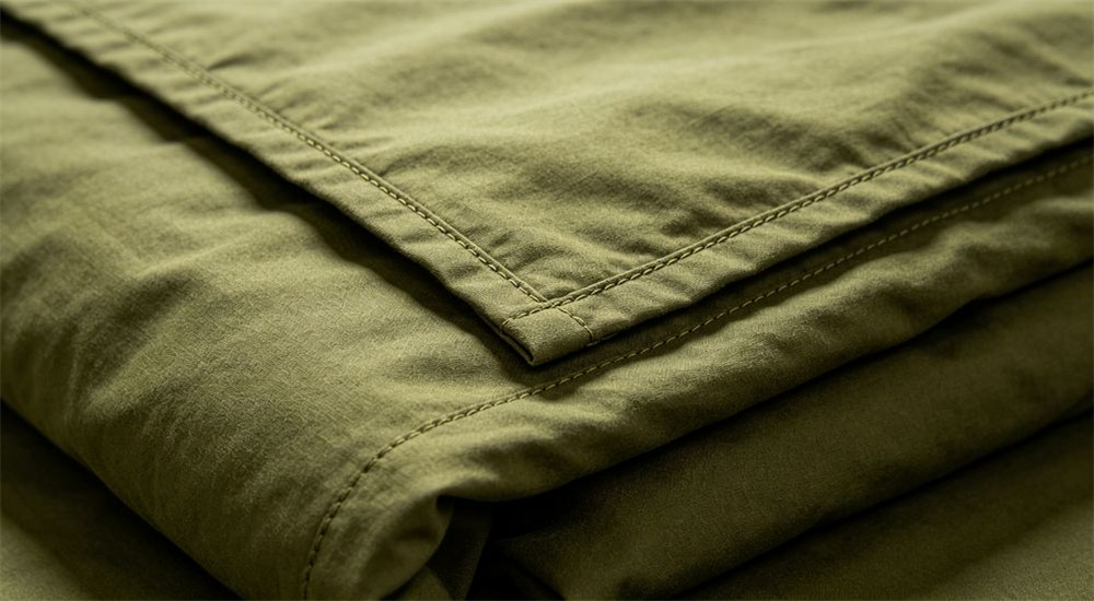 Close up of reinforced stitching on durable institutional bedding, strong seams on government procurement bed linen built to survive repeated industrial washing in public facilities, professional institutional textile photography with bright even lighting for government procurement buyers