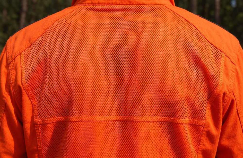 Side view of breathable mesh panel detail on orange mesh breathable wildland firefighting clothing for forest fire suit ventilation and wildland fire gear all day wear comfort