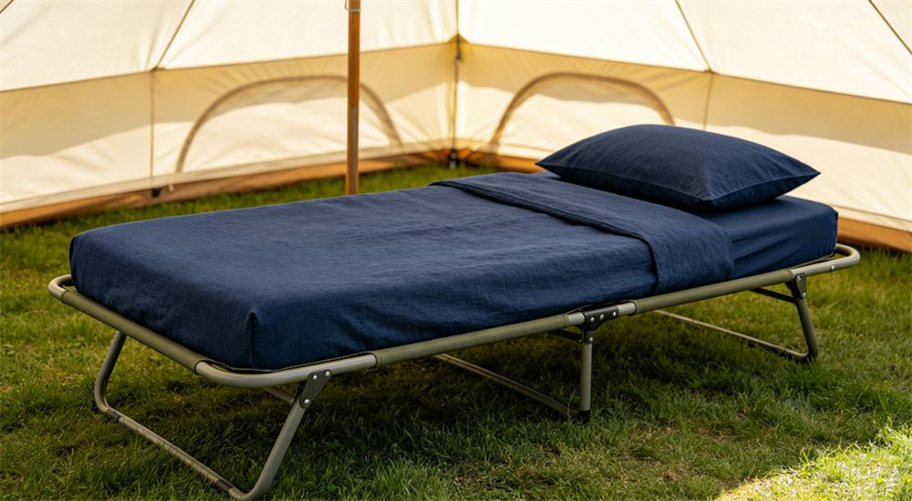 Side angle of close view of navy blue poly cotton relief bedding fabric arranged inside a field tent, durable mid weight humanitarian bedding for longer displacement camp use, through weeks of shared washing in field shelter conditions.