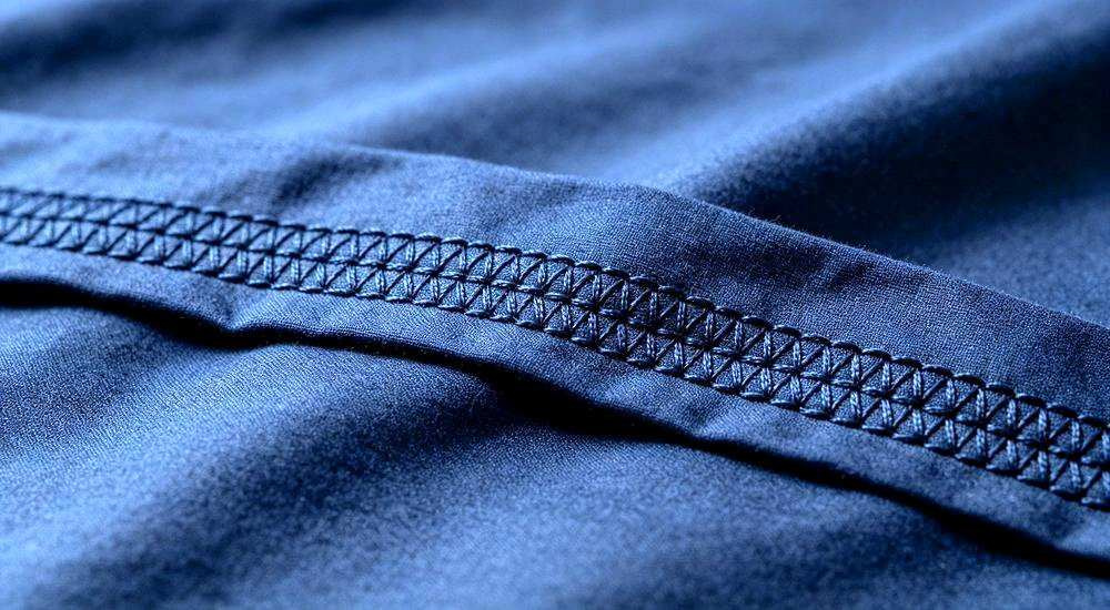 Close up of reinforced double stitching on navy workforce camp bedding seam, heavy duty construction camp bedding built for repeated industrial washing for construction camp bedding buyers sourcing durable linen.