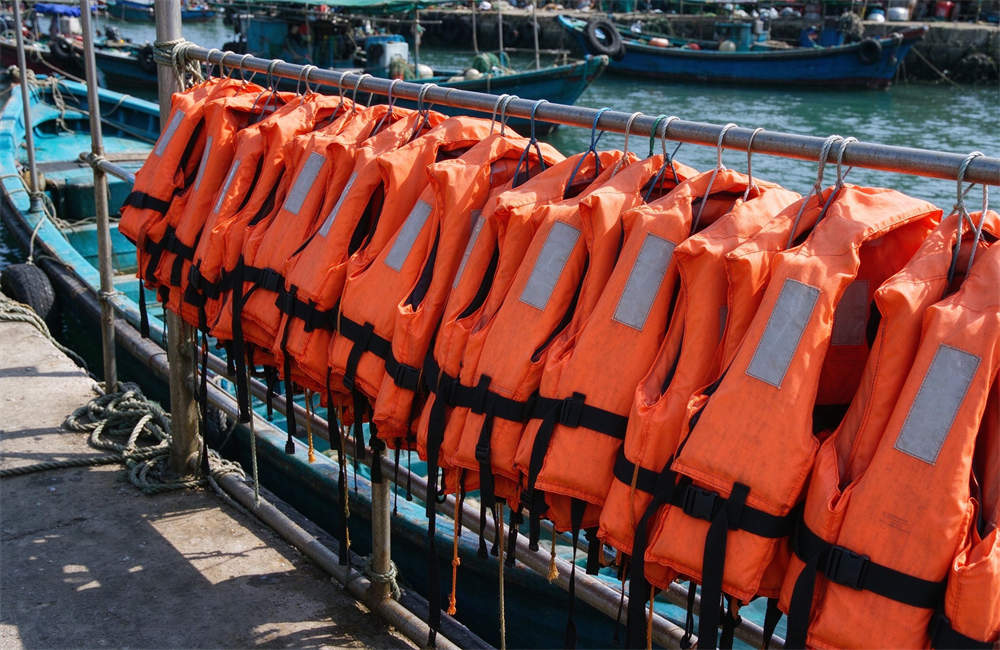 Orange life jackets hanging on the railing of a small fishing boat dock, ready for use, life jacket bulk order for coastal safety. Orange life jackets hanging on the railing of a small fishing boat dock, ready for use, life jacket bulk order for coastal safety.