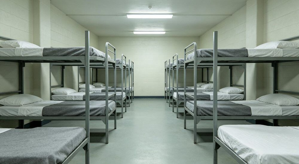 Interior view of correctional facility institutional dormitory scene with grey heavy institutional bulk bedding on metal bunk beds, tear-resistant sheet and duvet cover sets for wholesale correctional supply in a secure room Ideal for wholesale secure institutional and high-density dormitory
