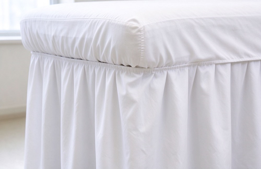 Bed skirt hem frill closeup showing layered drape and stitched edge on massage table, wholesale bed skirt classic style, spa table covers finishing detail