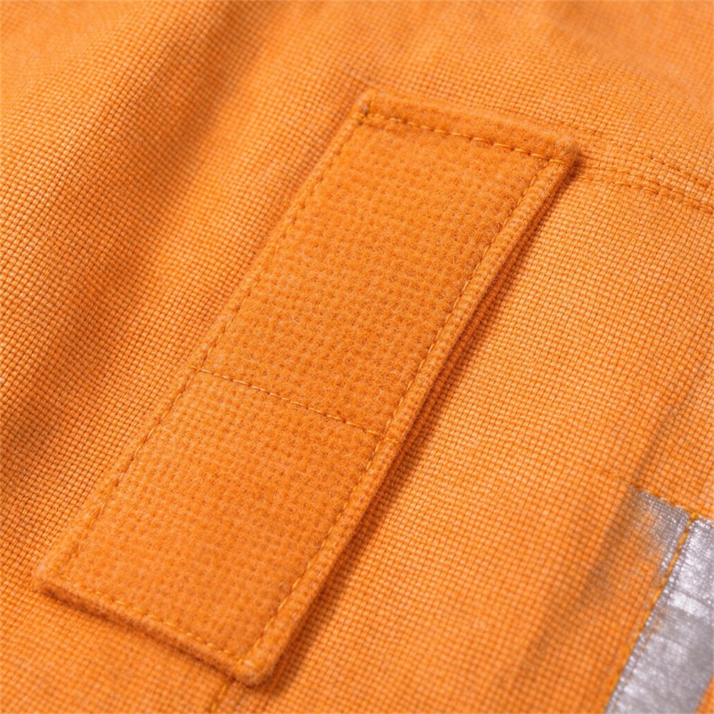 Close-up macro detail of Nomex IIIA outer shell fabric texture showing woven aramid fiber pattern and flame resistant surface with ruler for scale