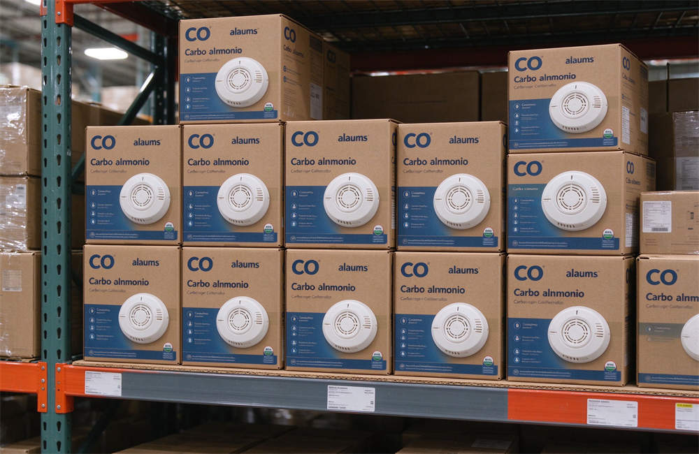 Cardboard boxes of CO alarms stacked on warehouse shelves, bulk carbon monoxide detectors for relief distribution and wholesale emergency safety supplies