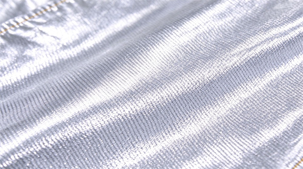 Close up detail of heavy duty protective aluminized high temperature coverall, Close up of silver aluminum foil protective suit fabric, reflective para aramid, demonstrating professional info use in industrial safety environment, designed for wholesale bulk supply and industrial safety procurement.