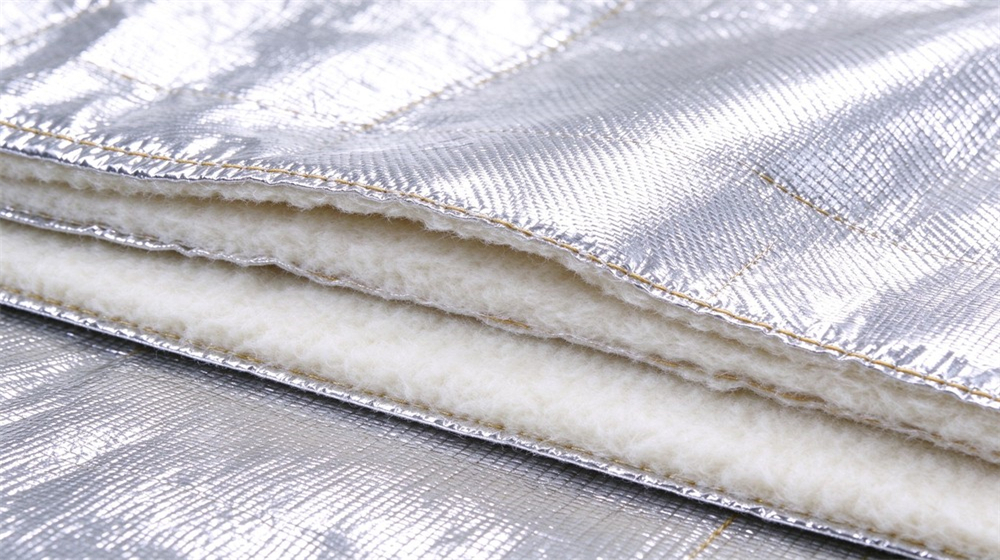 Close up detail of heavy duty protective aluminized high temperature coverall, Multi-layer cross section of aluminum foil protective suit fabric, foil insulation and, demonstrating professional info use in industrial safety environment, designed for wholesale bulk supply and industrial safety procurement.