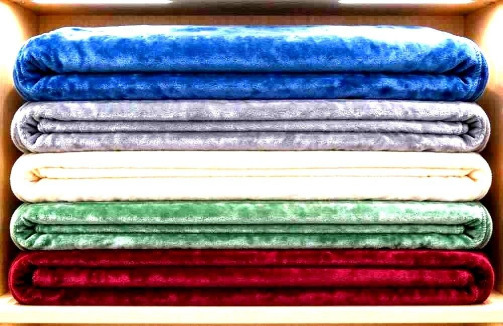 Stacked fleece and cotton medical blankets in a bright clinic store room, showing first aid blankets bulk for health facility stock