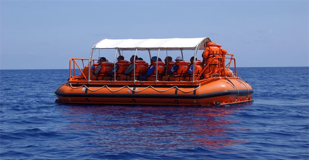 Wide view of enclosed orange life raft with survivors in open ocean showing maritime abandonment and survival Wide view of enclosed orange life raft with survivors in open ocean showing maritime abandonment and survival