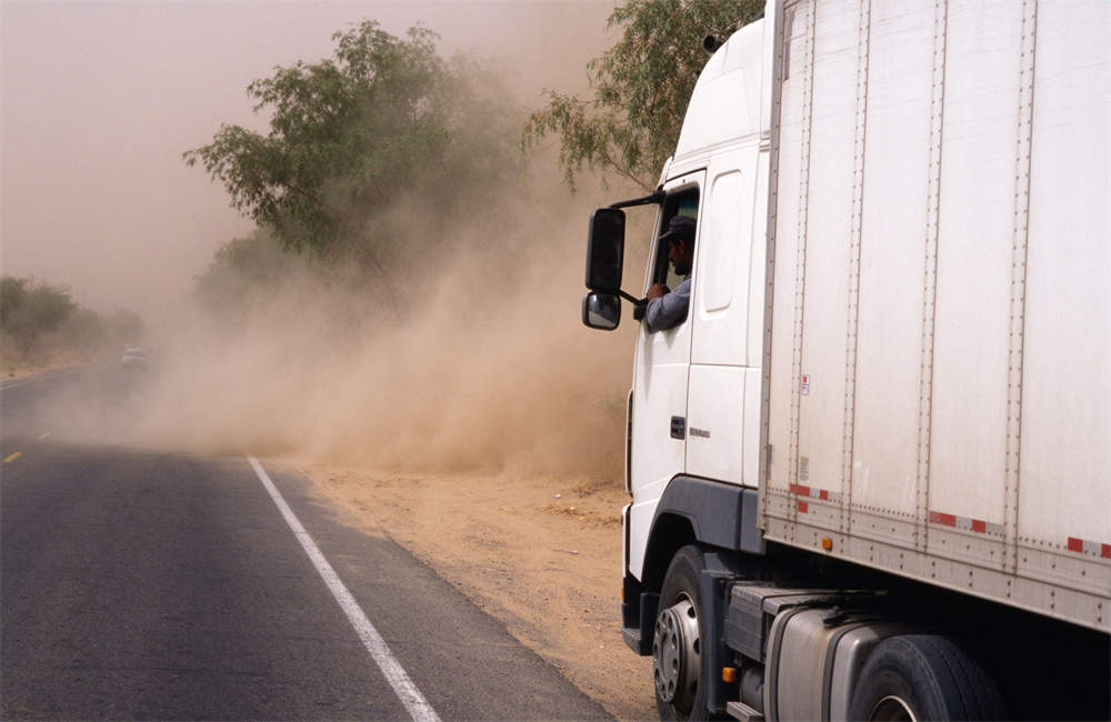 White semi truck pulled over on road during sandstorm, driver waiting out dust storm, commercial vehicle emergency kit